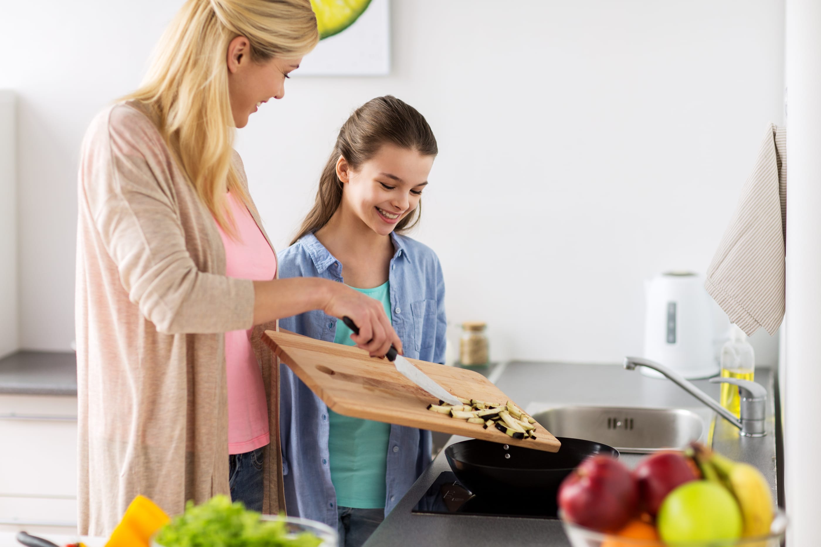 Mother cooking with daughter, teaching kids about money