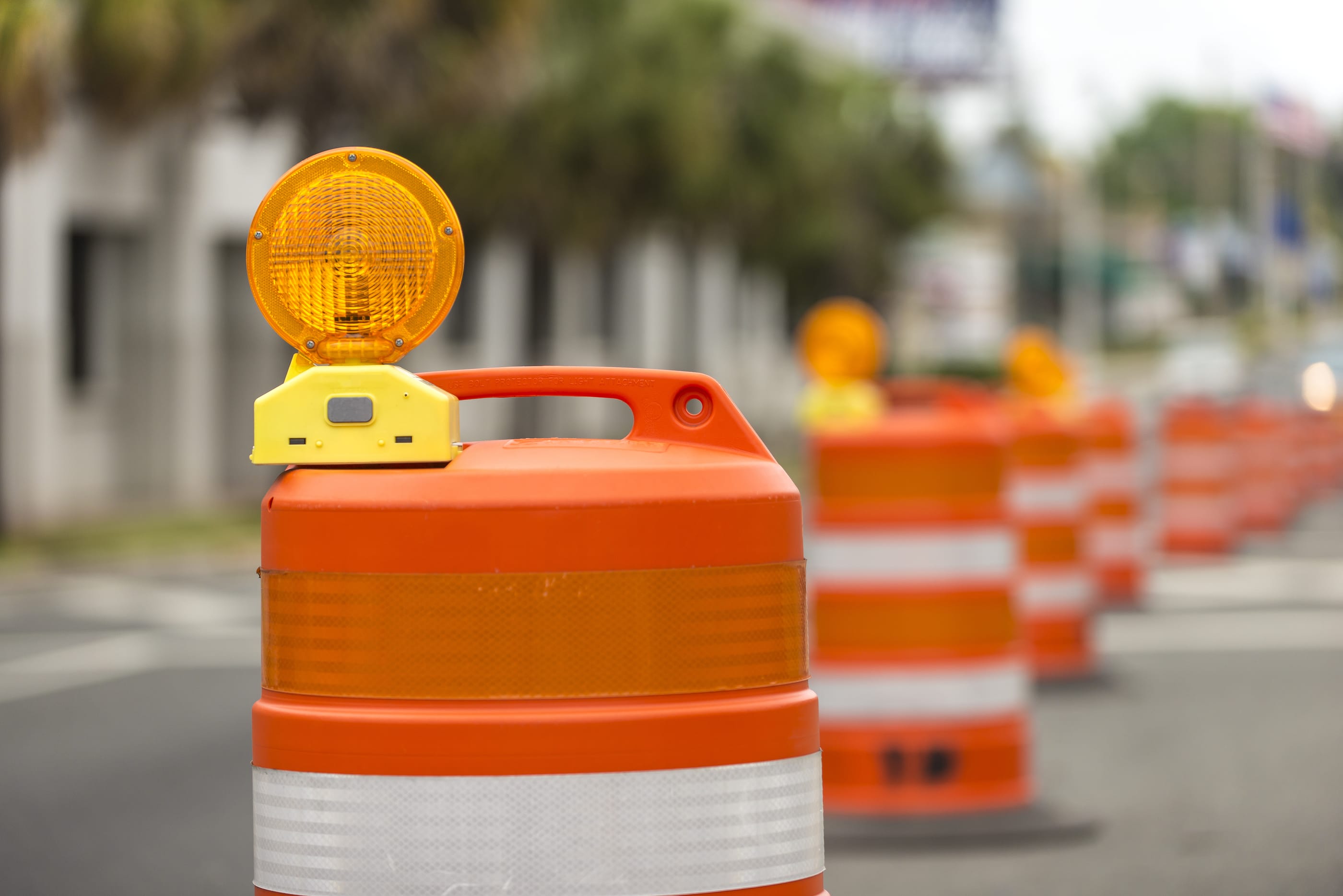 long line of orange traffic barrier barrels to detour traffic around construction zone shallow depth of field