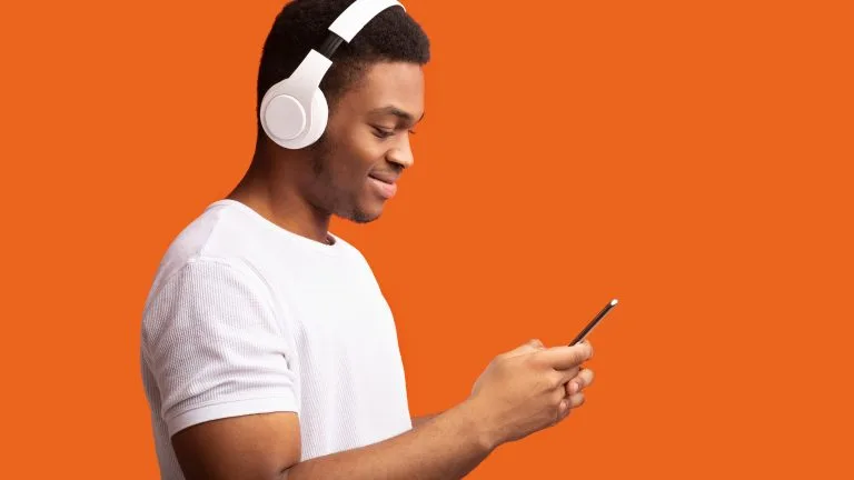 Enjoy Music. Smiling Man Listening To Podcast On Cellphone