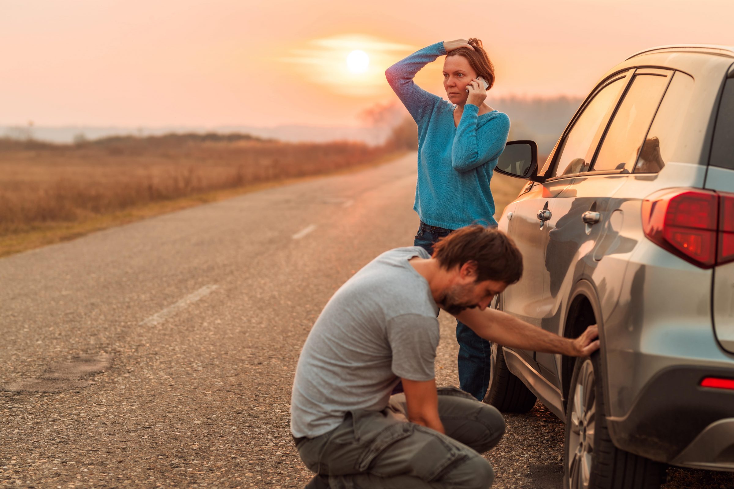 couple on side of road with flat tire